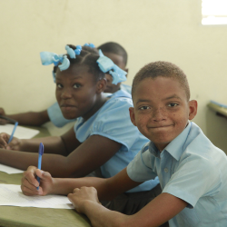 Students in uniform writing in class at FWAL Community School in Haiti