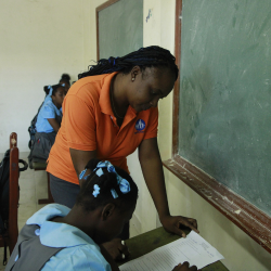eacher supporting a student during class at FWAL Community School in Haiti