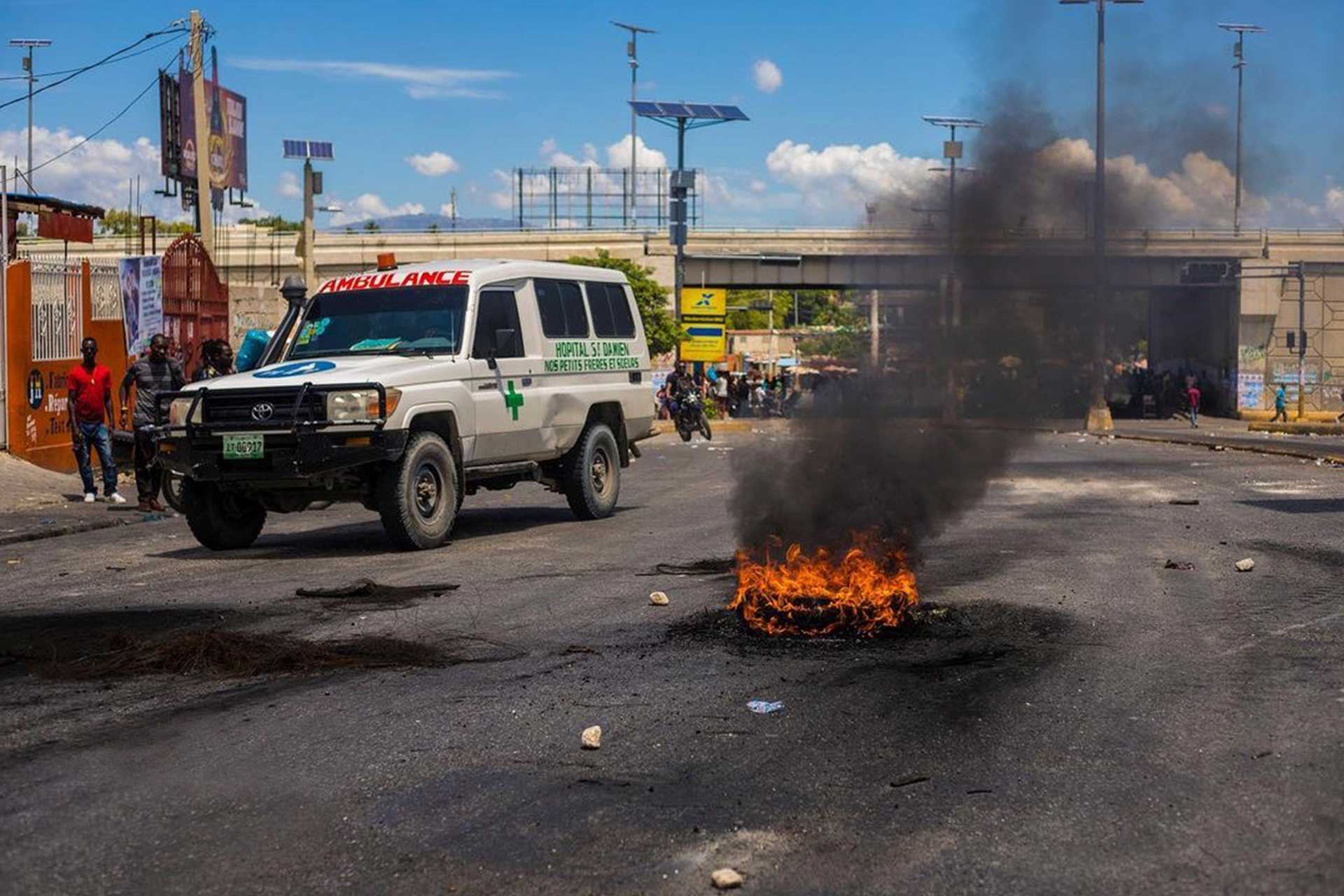 Image of ambulance driving by burning tire in the middle of the road