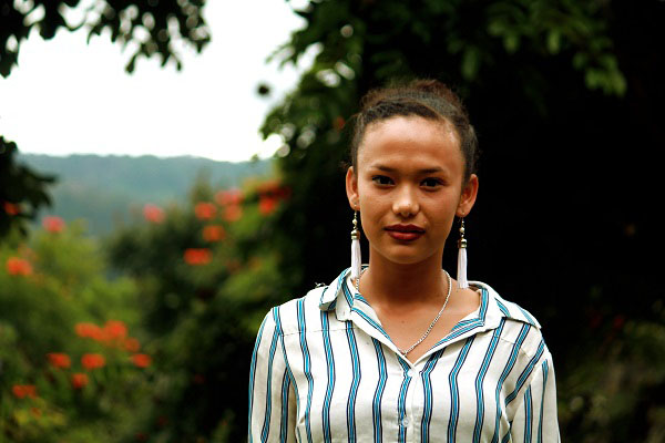 NPH Honduras_Young woman with dark hair pulled back and long white earrings in front of natural landscape