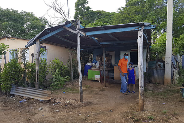 Man in an orange shirt standing in front of a home in the Dominican Republic